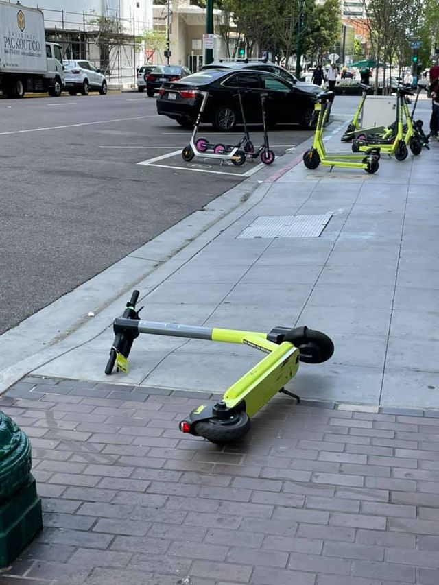 Despite a corral in the street, scooters get left on sidewalks.